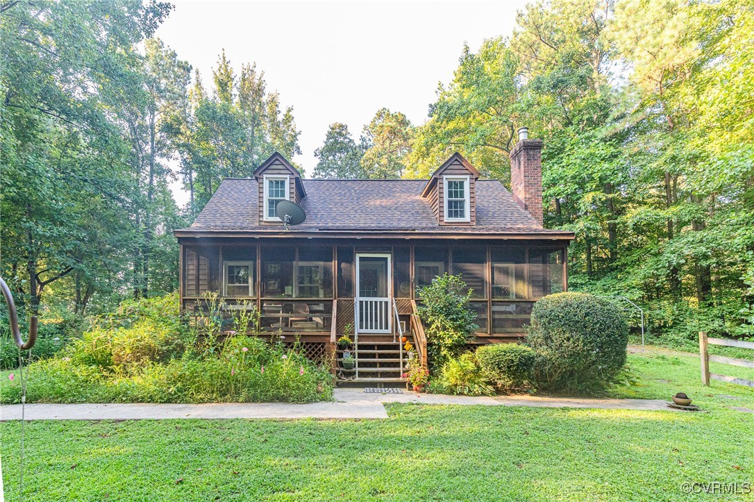 Cape cod home featuring a front lawn and a sunroom