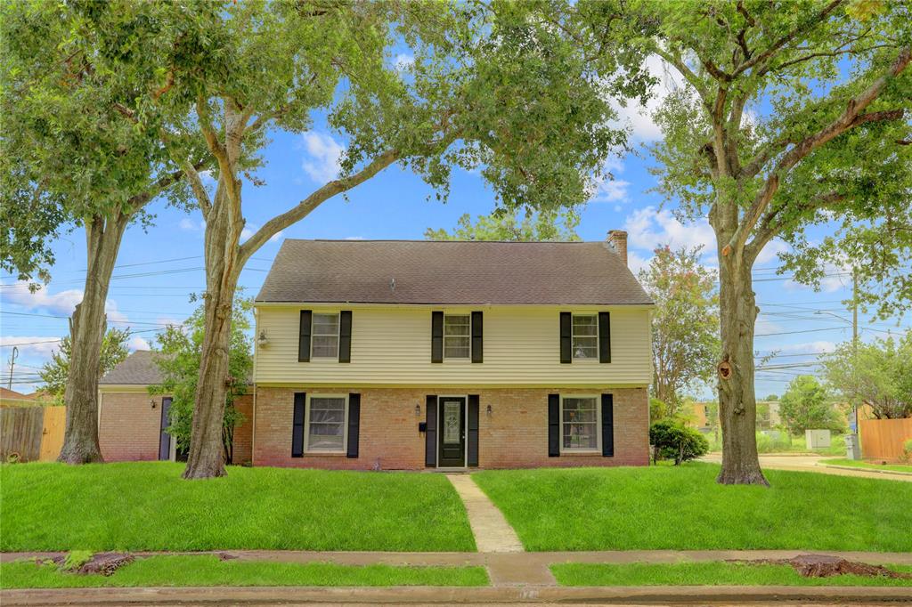 a view of a brick house next to a yard with big trees