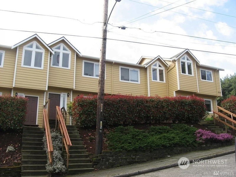 a view of a house with wooden fence next to a yard