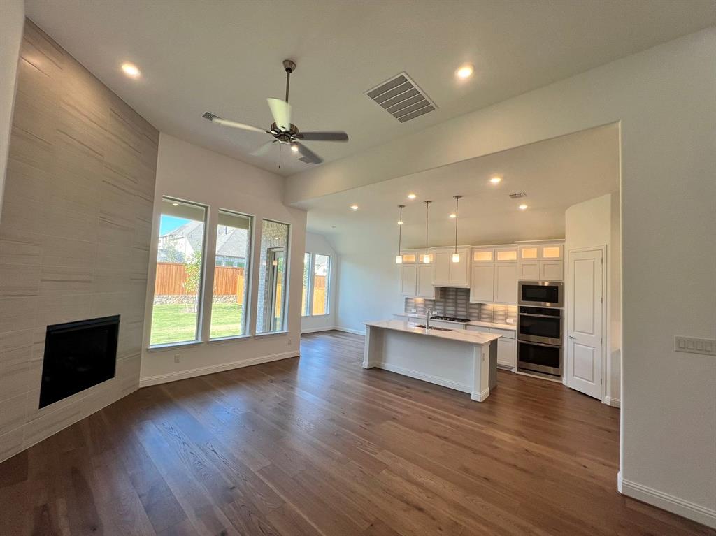 a view of a big room with wooden floor and a kitchen