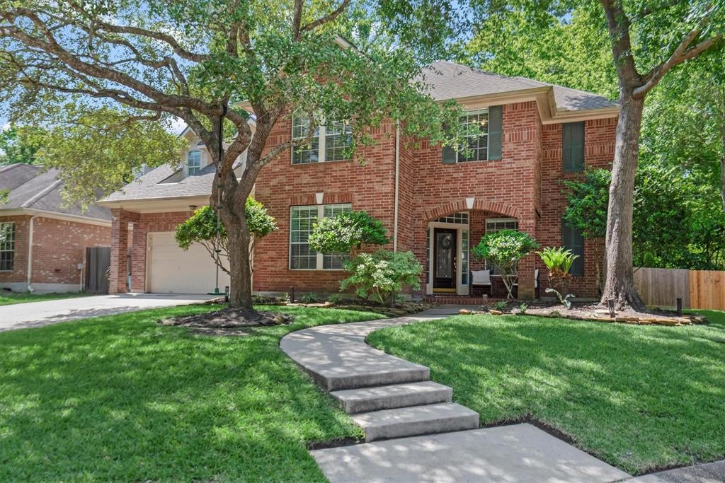 a front view of a house with a yard and large tree