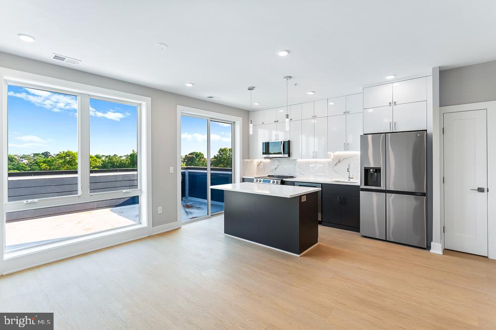 a kitchen with a refrigerator a sink and white cabinets