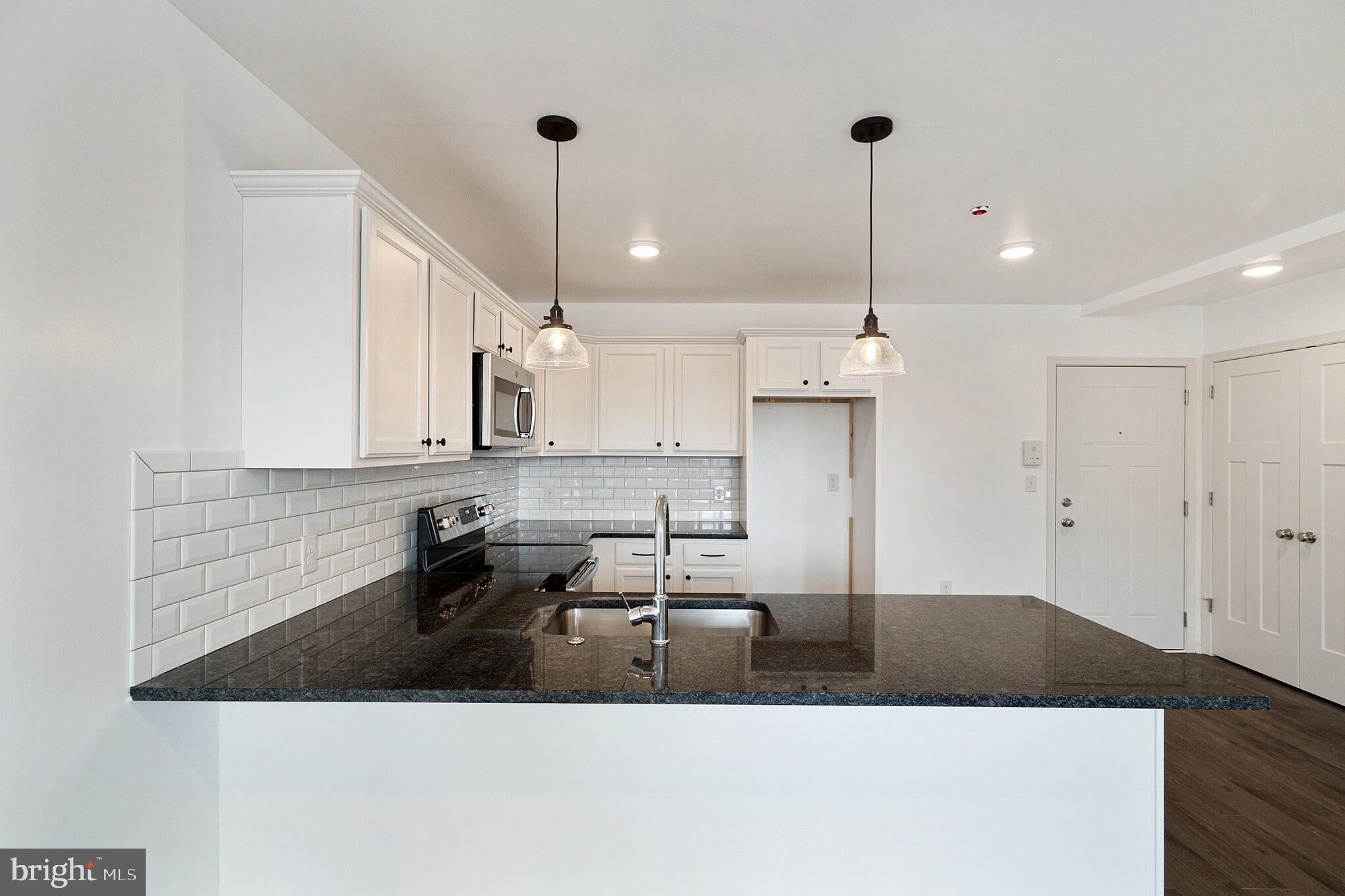 a kitchen with kitchen island granite countertop a sink a counter and cabinets