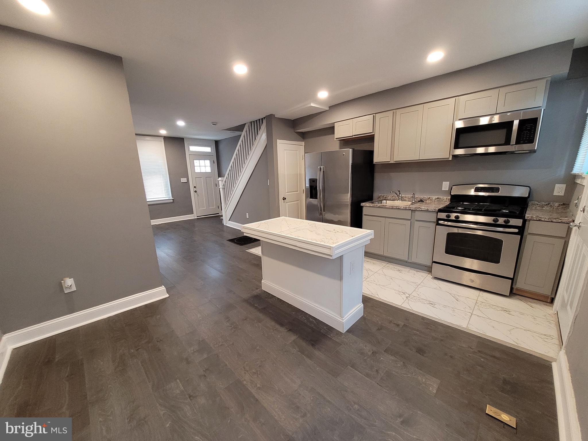 a kitchen with stainless steel appliances a stove top oven a sink and a refrigerator