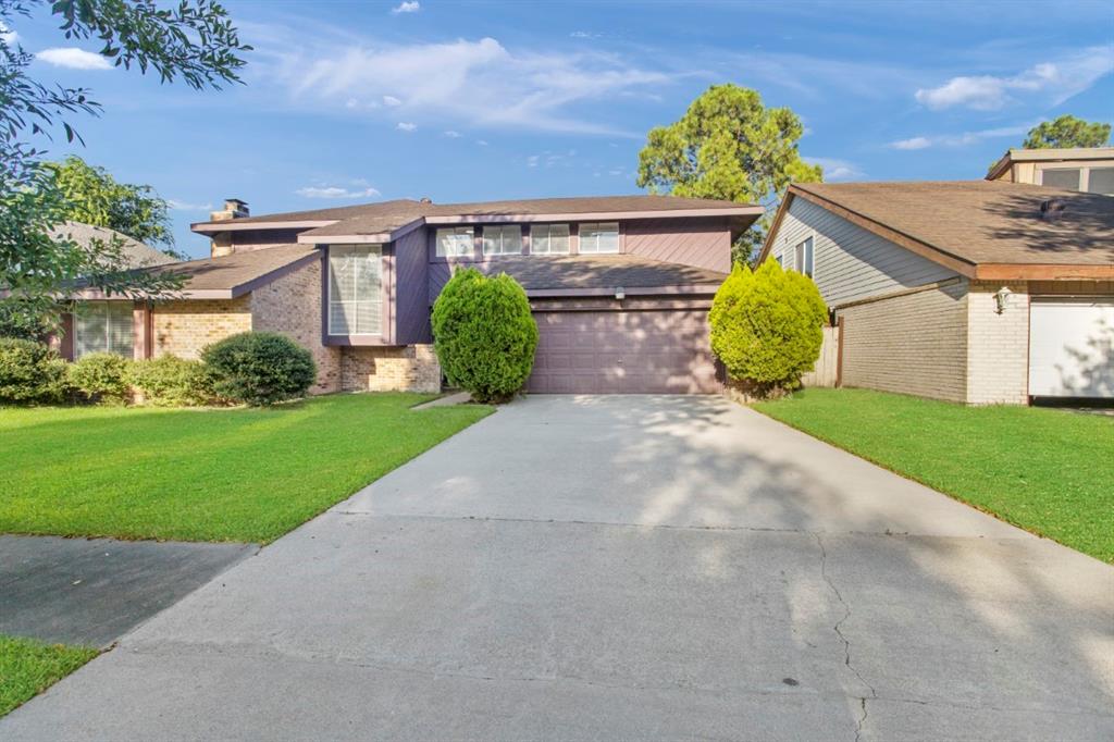 a view of a house with a small yard and a large parking space