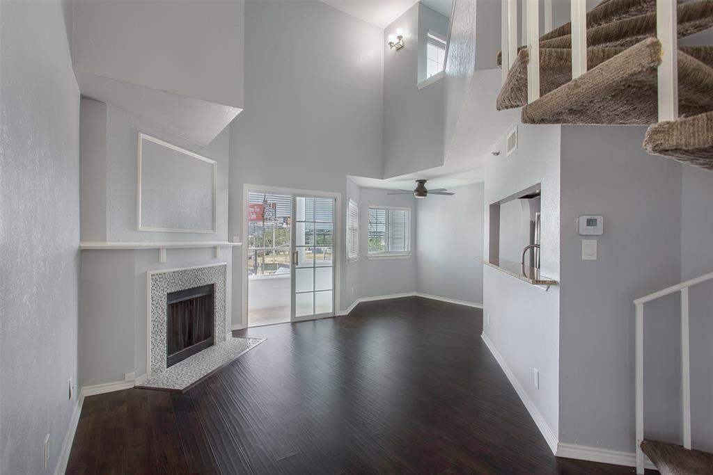 a view of an empty room with wooden floor and a fireplace