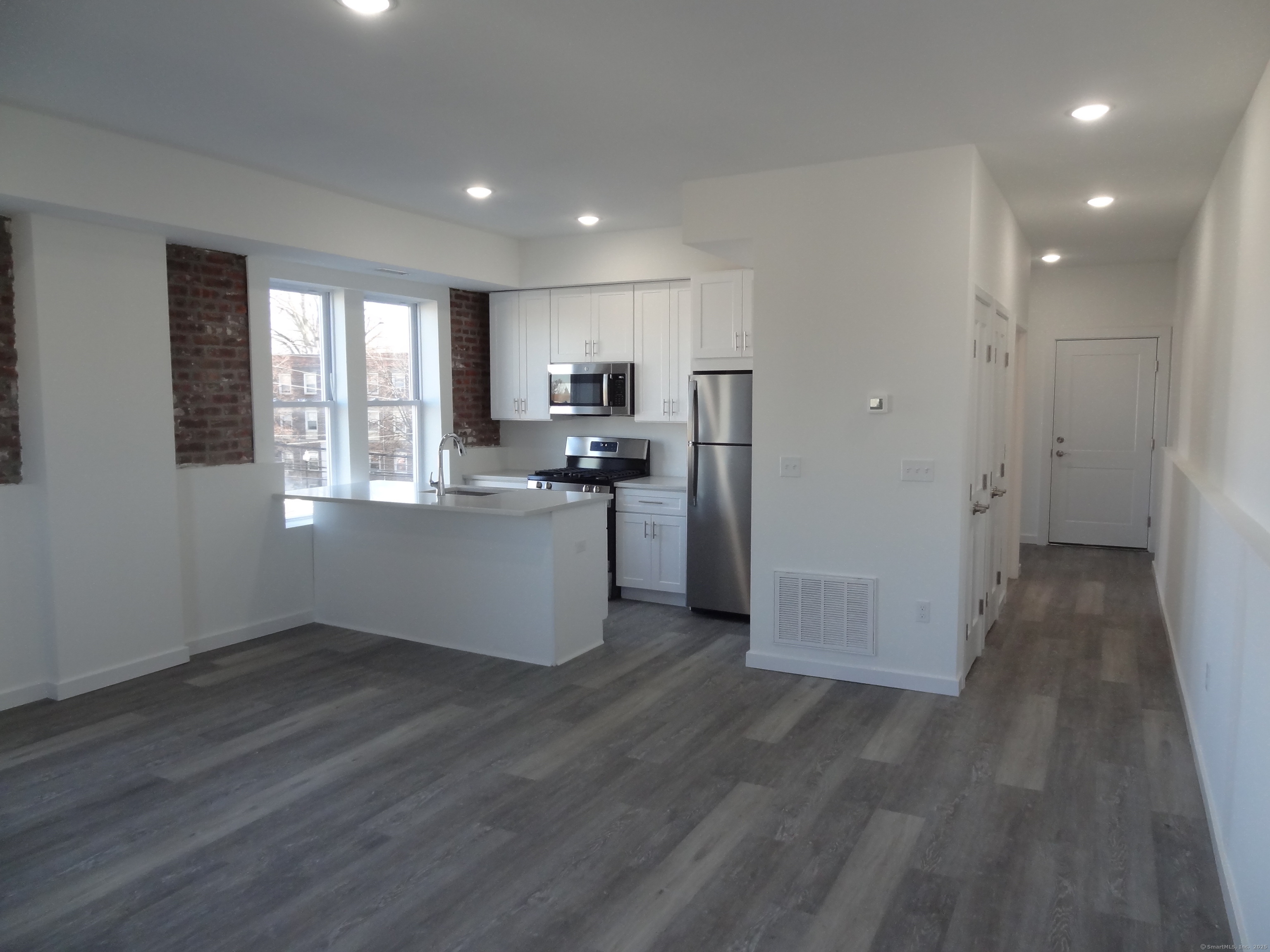 a view of kitchen with cabinets appliances wooden floor and window