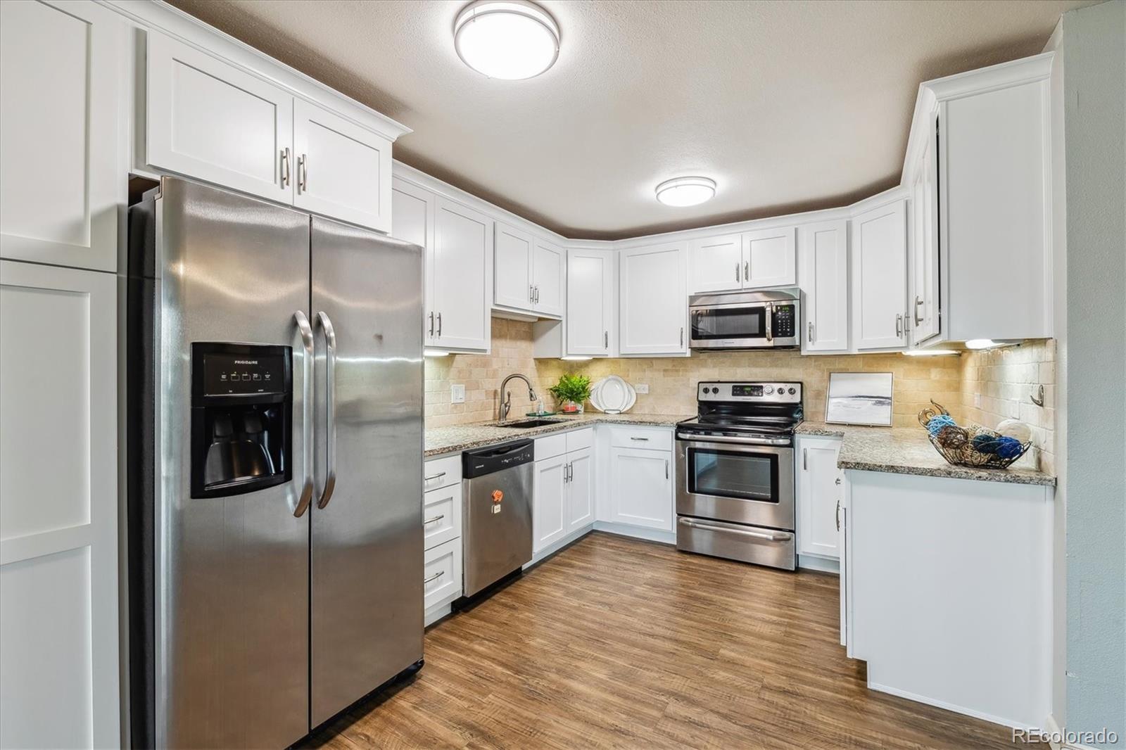 a kitchen with granite countertop a refrigerator stove and microwave