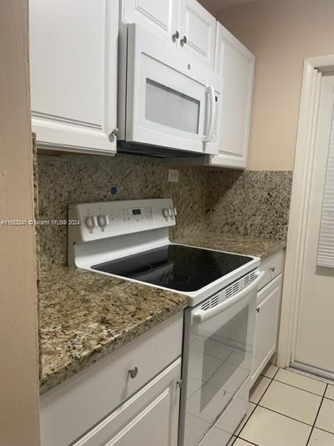 a kitchen with granite countertop white cabinets stainless steel appliances and a counter space