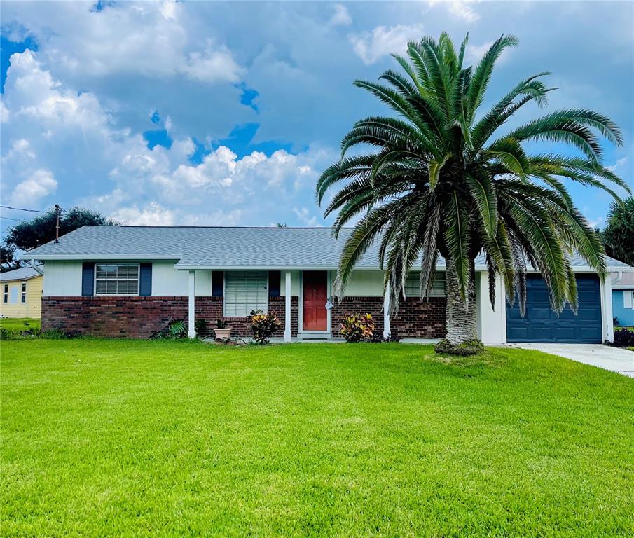 a view of a house with a yard and palm trees