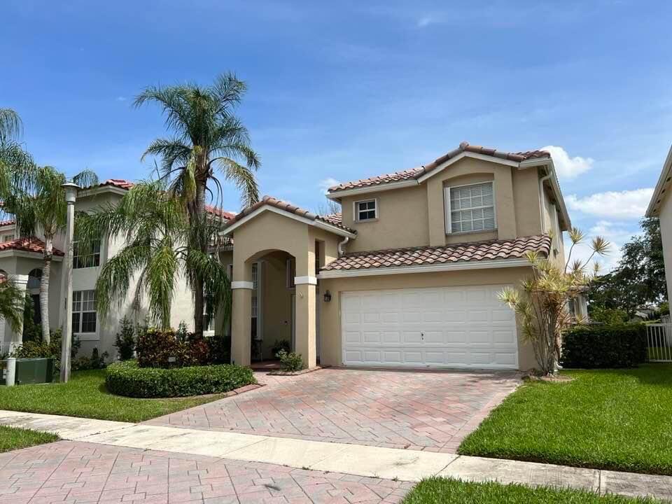 a front view of a house with a garden and trees