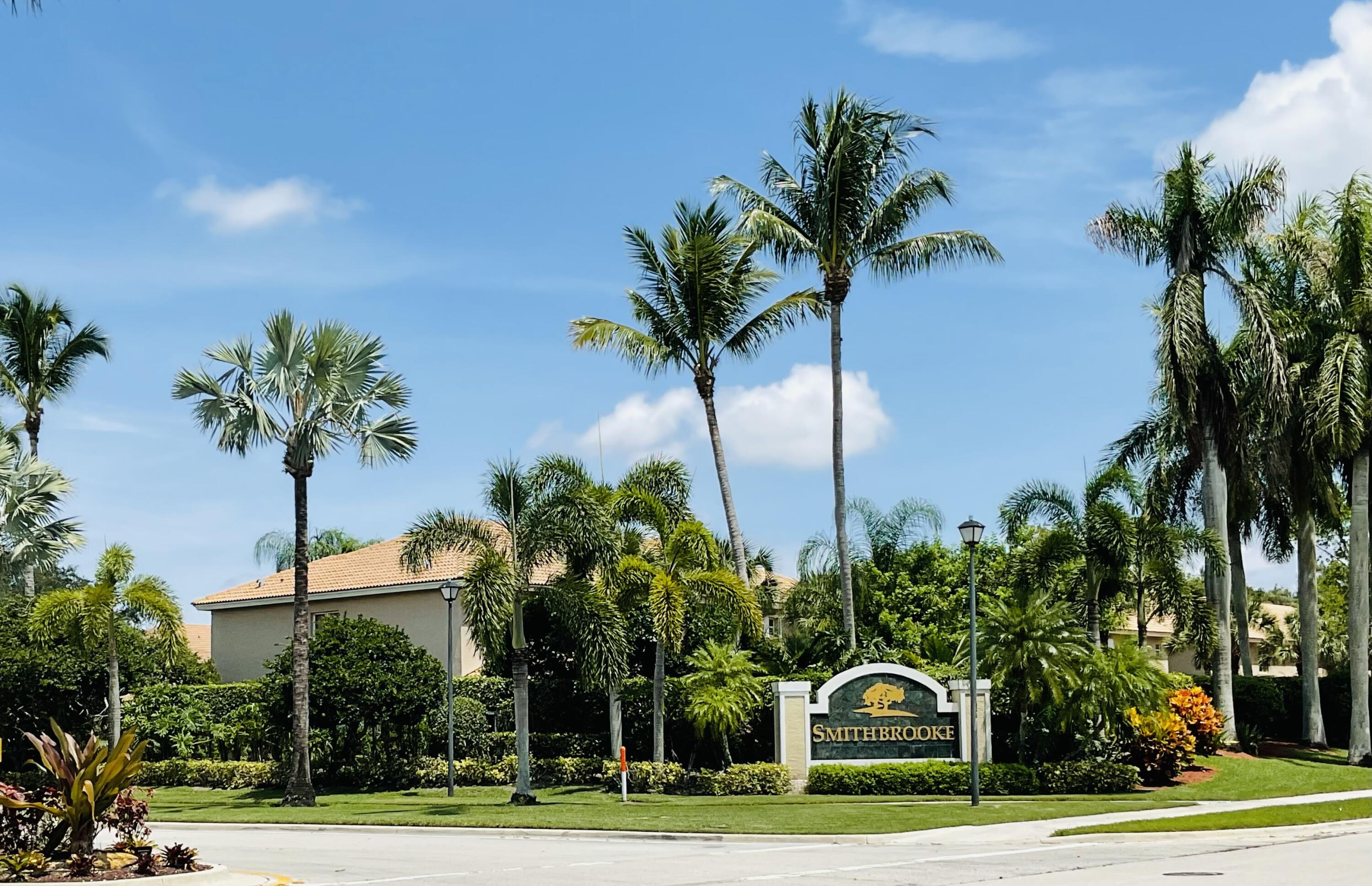 a front view of a house with a yard and palm trees