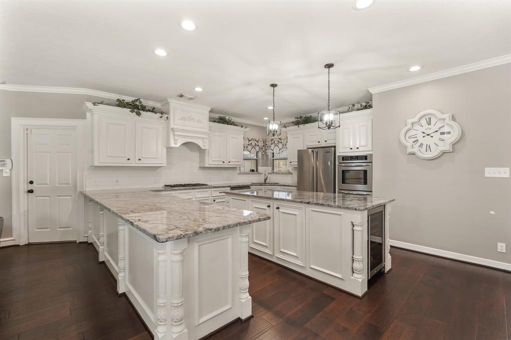 This masterfully-equipped kitchen features a kitchen island, an abundance of cabinetry and hardware, TONS of counter space, granite countertops, stainless-steel appliances, pendant and recessed lighting.