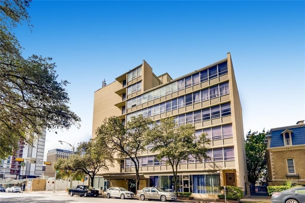 a front view of a building with lot of cars and trees