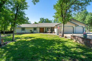 a view of a house with a yard and a large tree