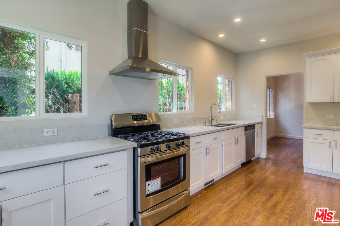 a kitchen with granite countertop a stove a sink and a refrigerator