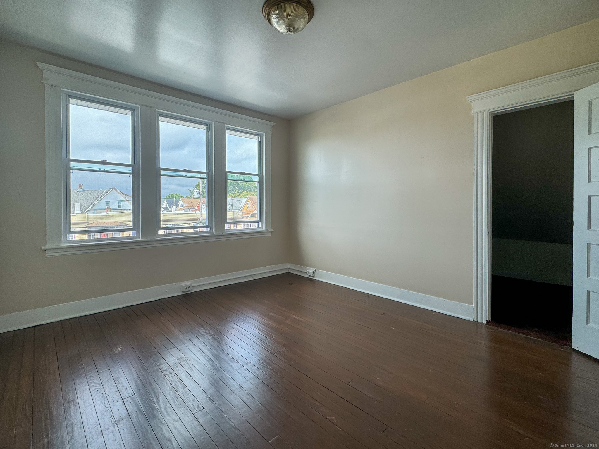 an empty room with wooden floor and windows