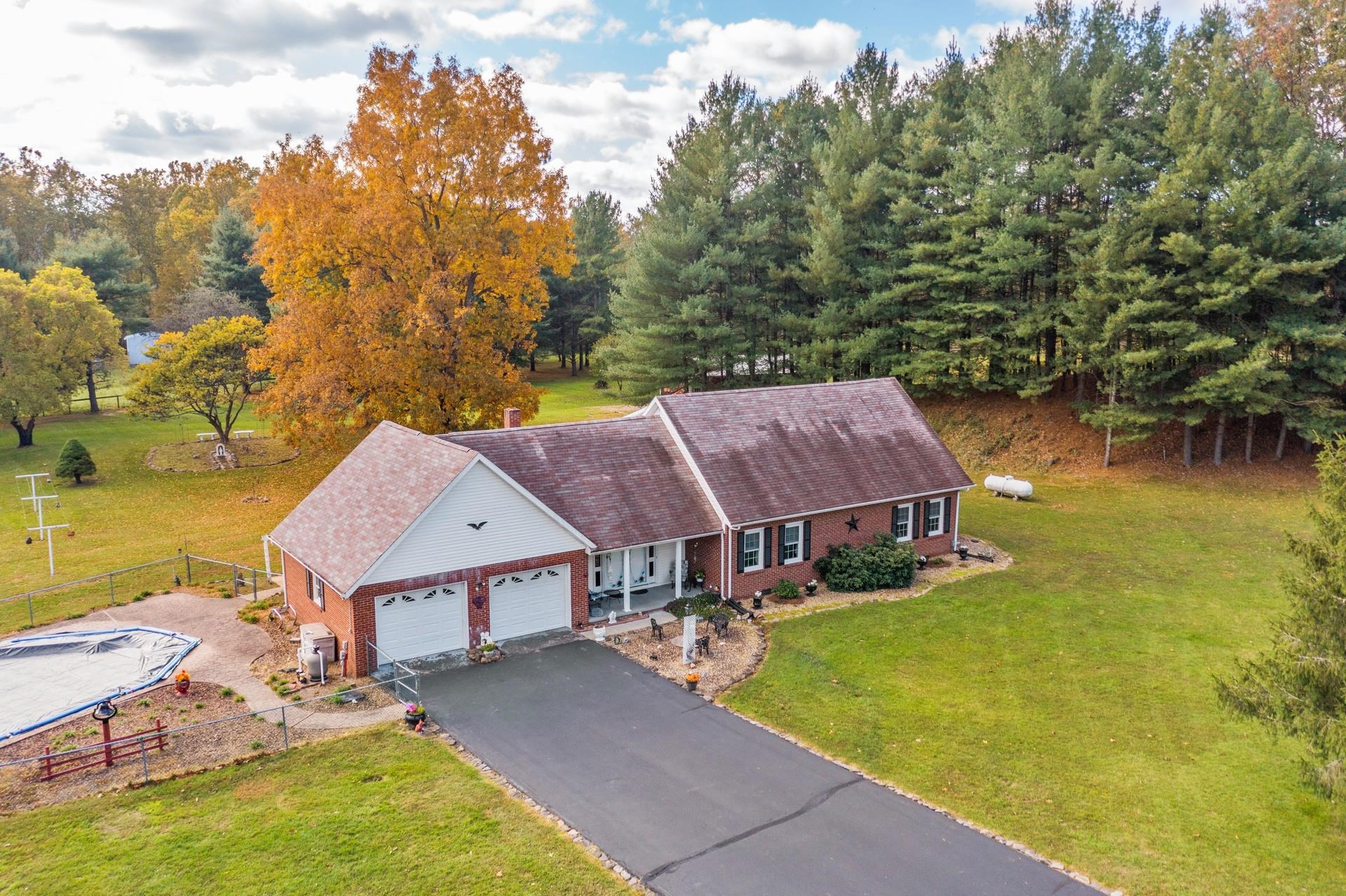 an aerial view of a house with swimming pool and large trees