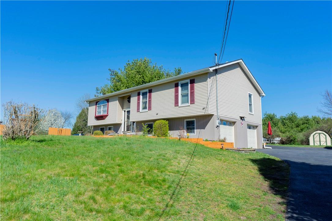 Bi-level home featuring a storage unit, a front lawn, and a garage