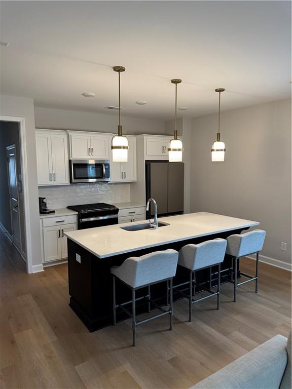 a kitchen with stainless steel appliances kitchen island a table chairs in it and white cabinets