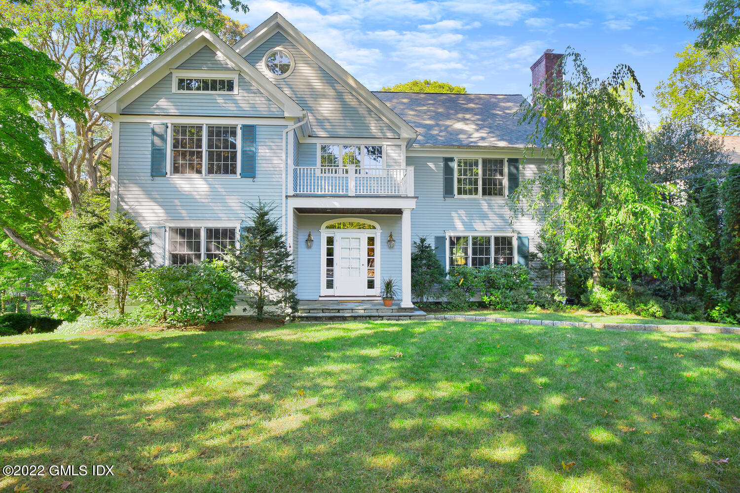 a front view of a house with a yard and trees