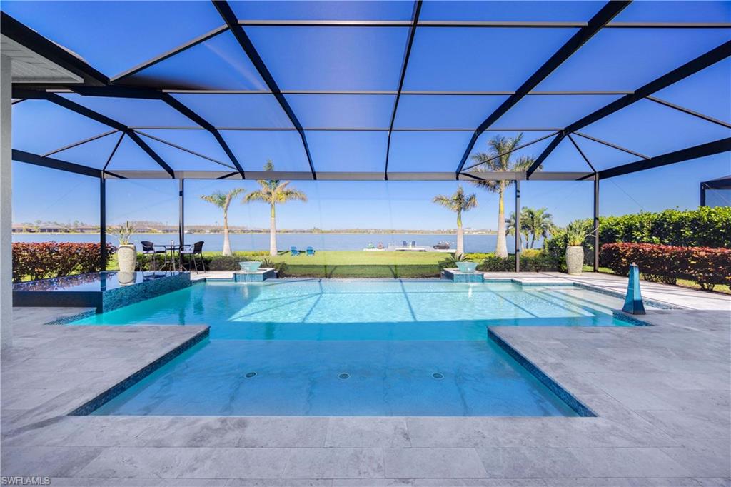 View of swimming pool featuring glass enclosure, a water view, and a patio