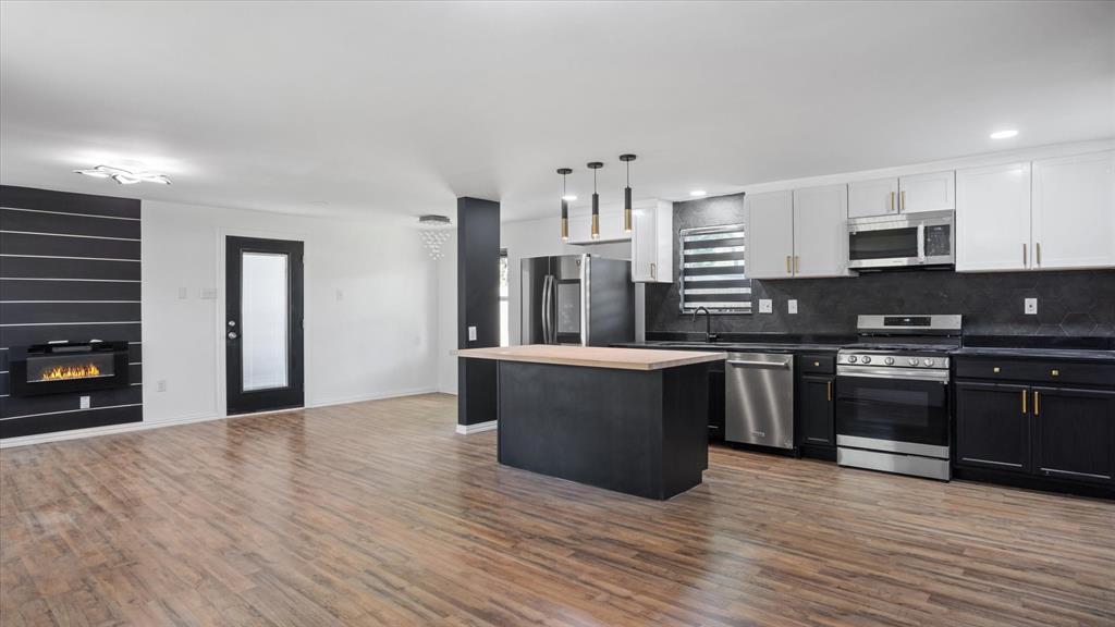 a large kitchen with stainless steel appliances granite countertop a stove and a refrigerator