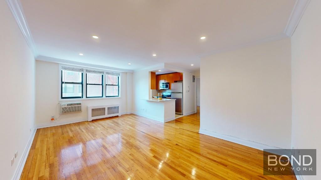 a view of a big room with wooden floor and windows