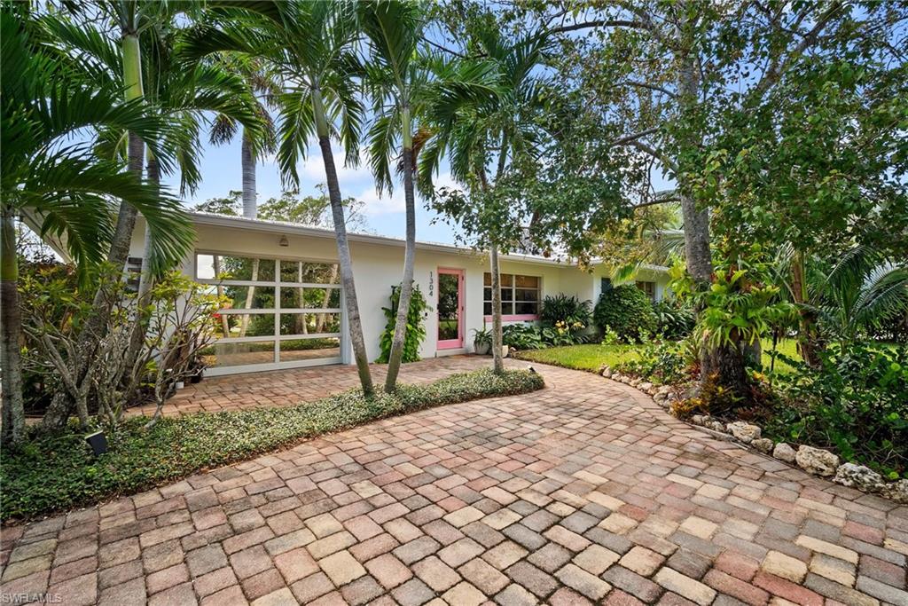 a front view of a house with a yard and potted plants