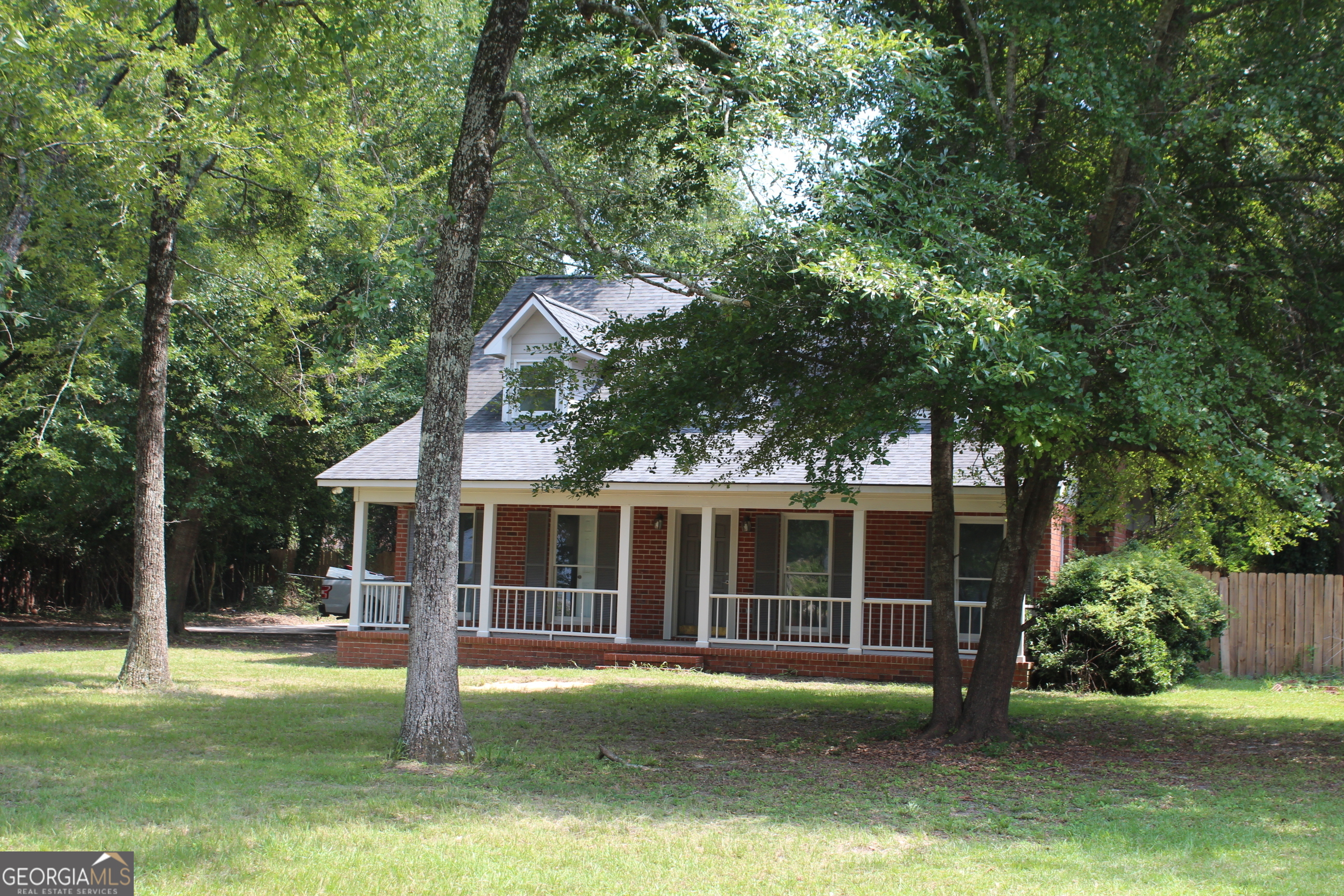 a view of a house with a yard deck and a large tree