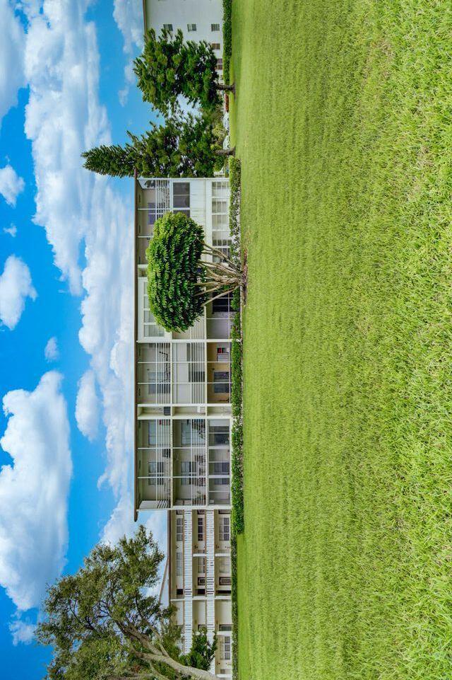 a view of a house with a big yard and large trees