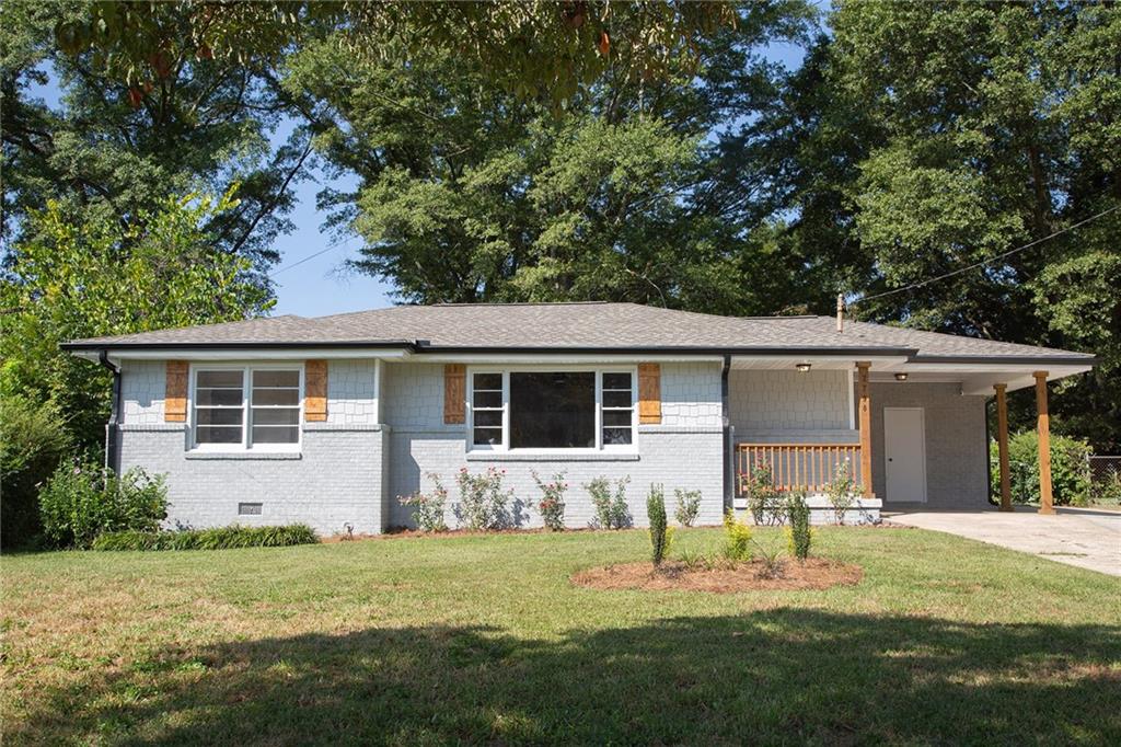 a front view of house with yard and trees in the background