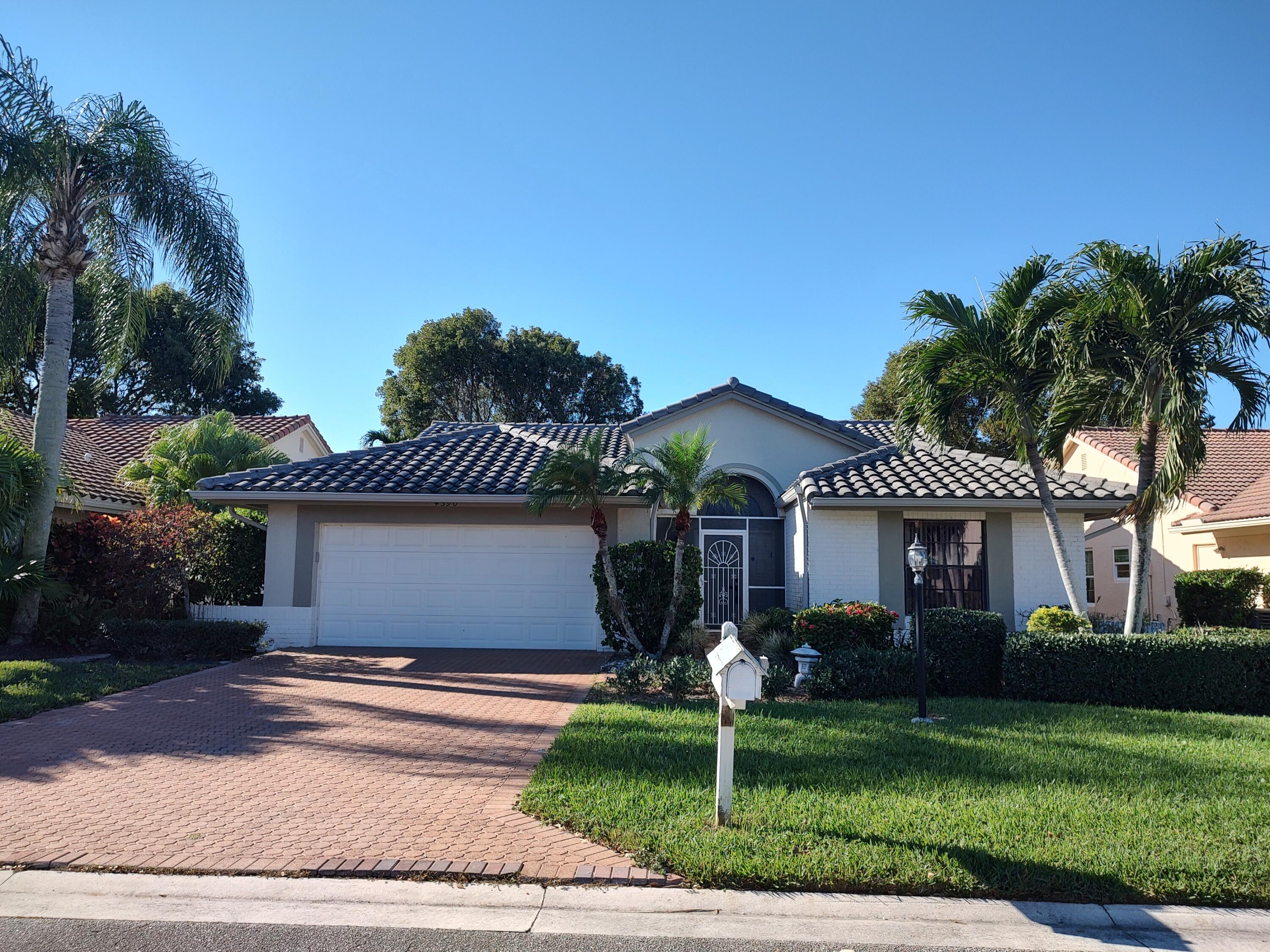 a front view of a house with a garden and palm tree