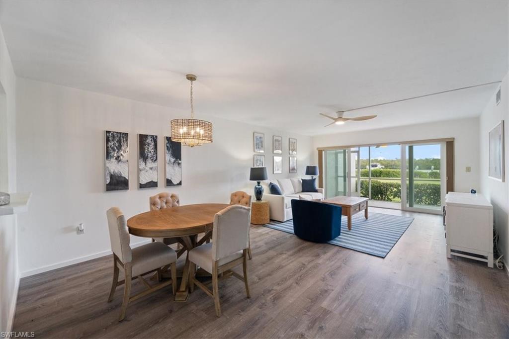 Dining room with dark hardwood / wood-style flooring and ceiling fan with notable chandelier