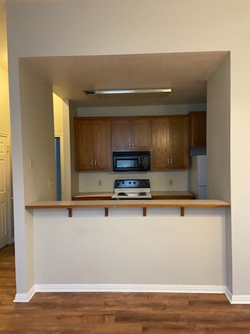 a view of kitchen with stainless steel appliances granite countertop cabinets and a wooden floor