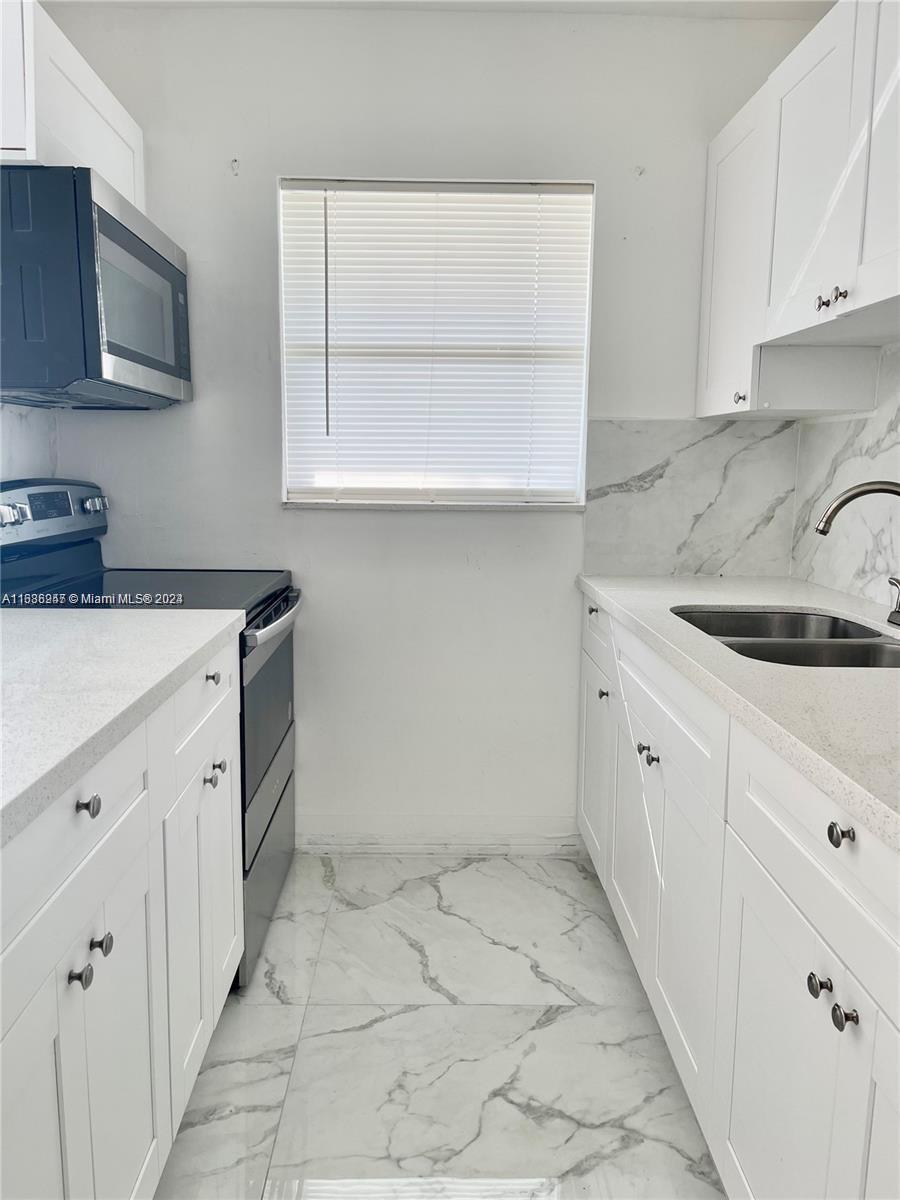 a kitchen with granite countertop white cabinets and white appliances