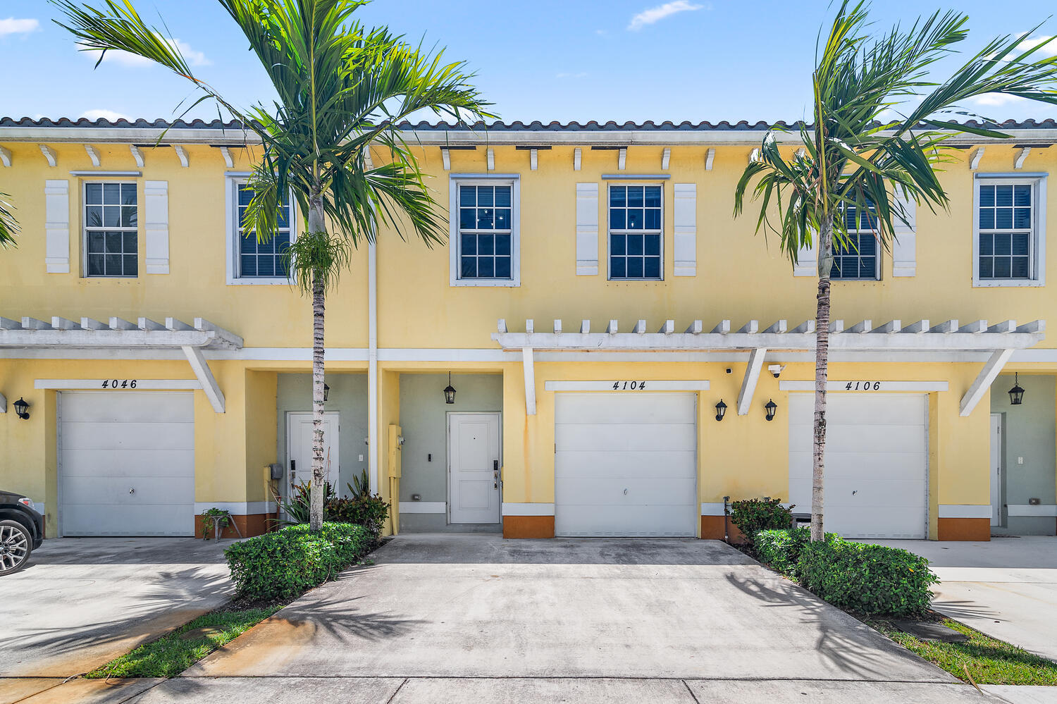 front view of a house with a yard and palm trees