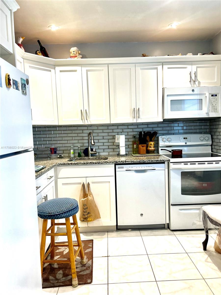 a kitchen with granite countertop a sink a stove and cabinets