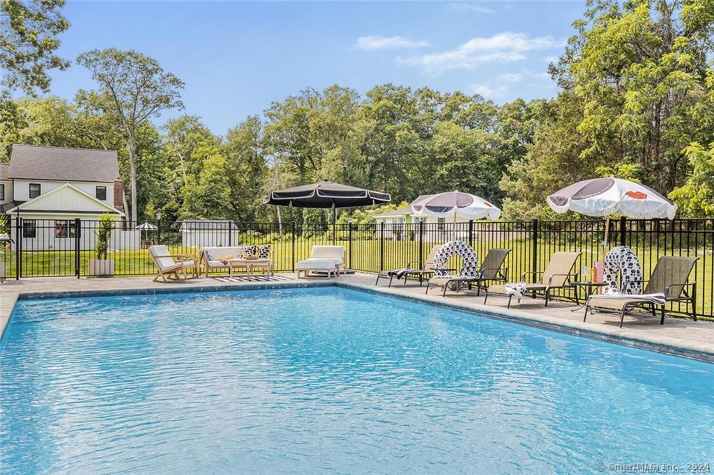 a view of a swimming pool with a table and chairs under an umbrella