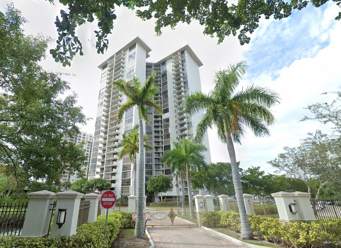 a front view of multi story residential apartment building with yard and sign board