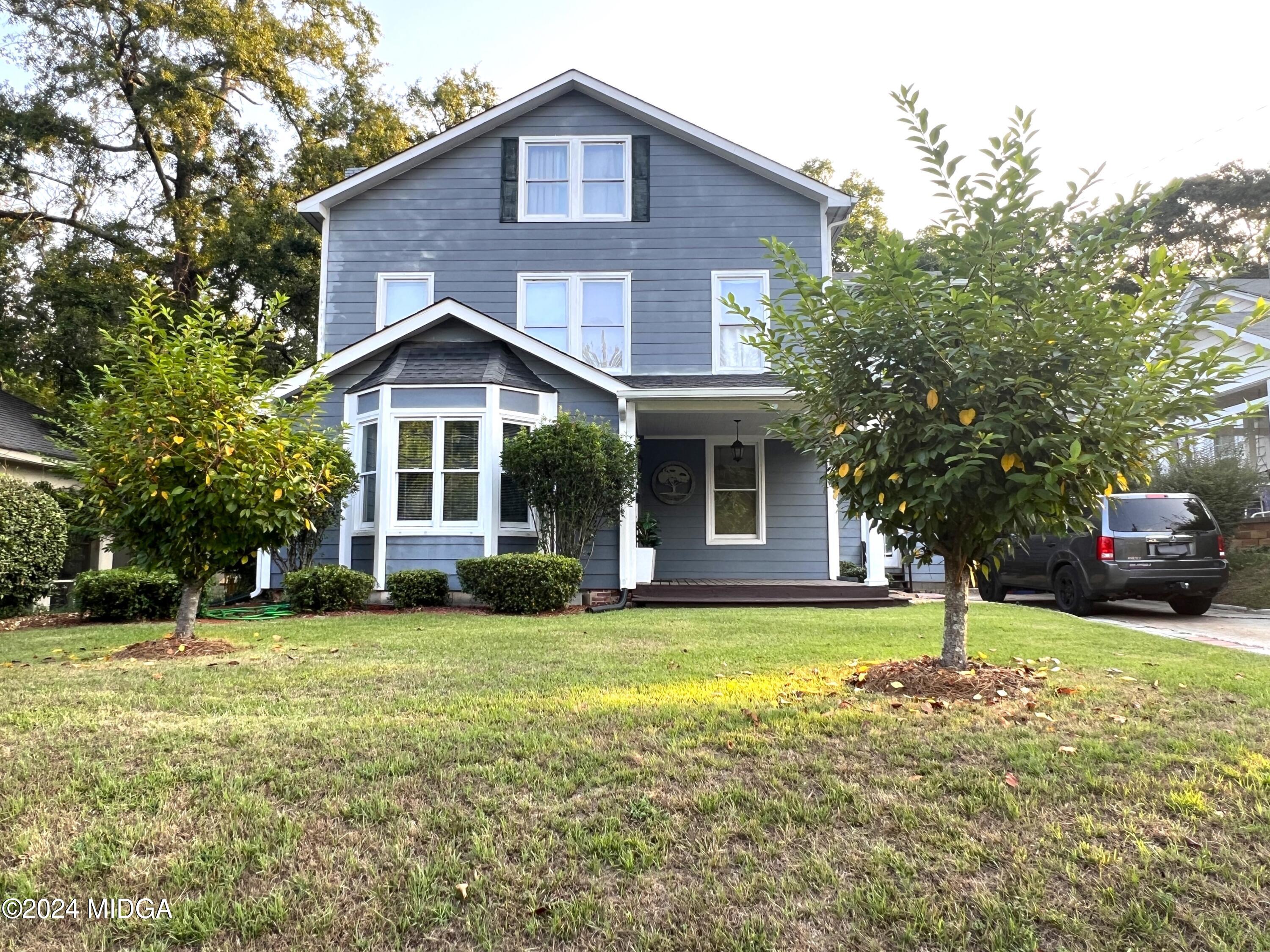 a view of a house with a yard patio and a tree