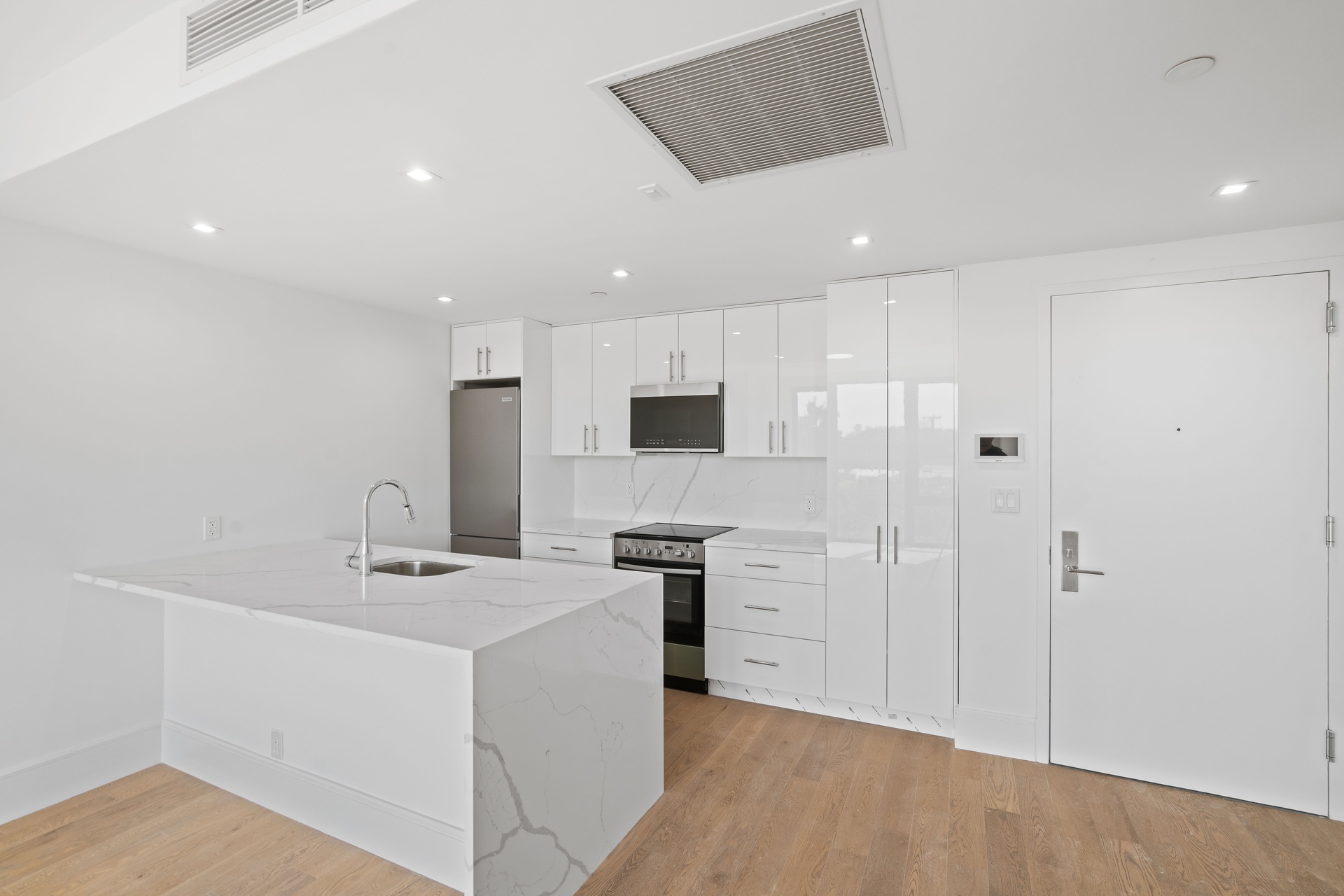 a view of kitchen with stainless steel appliances kitchen island sink refrigerator and cabinets