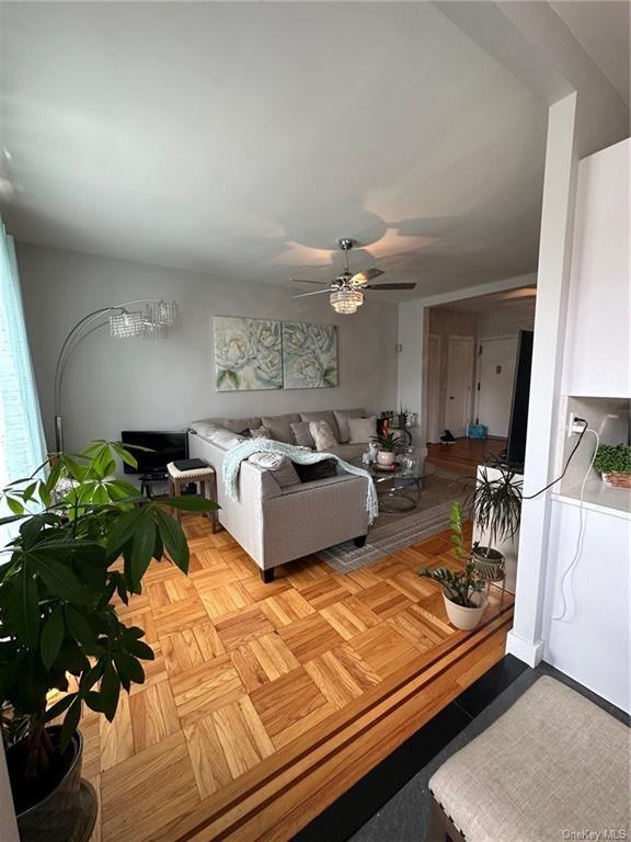 Living room featuring ceiling fan and light parquet floors