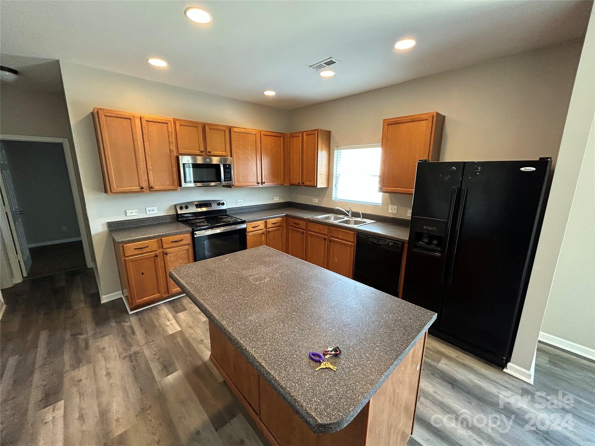 a kitchen with stainless steel appliances granite countertop a refrigerator a sink a stove a dining table and chairs