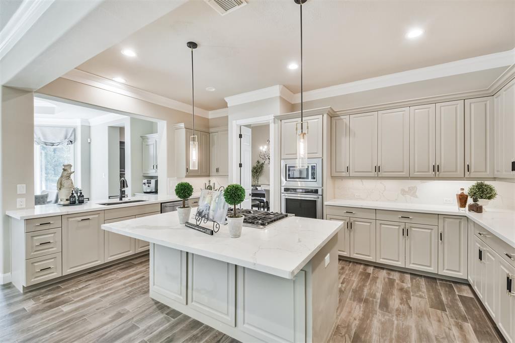 a kitchen with sink stove and white cabinets with wooden floor