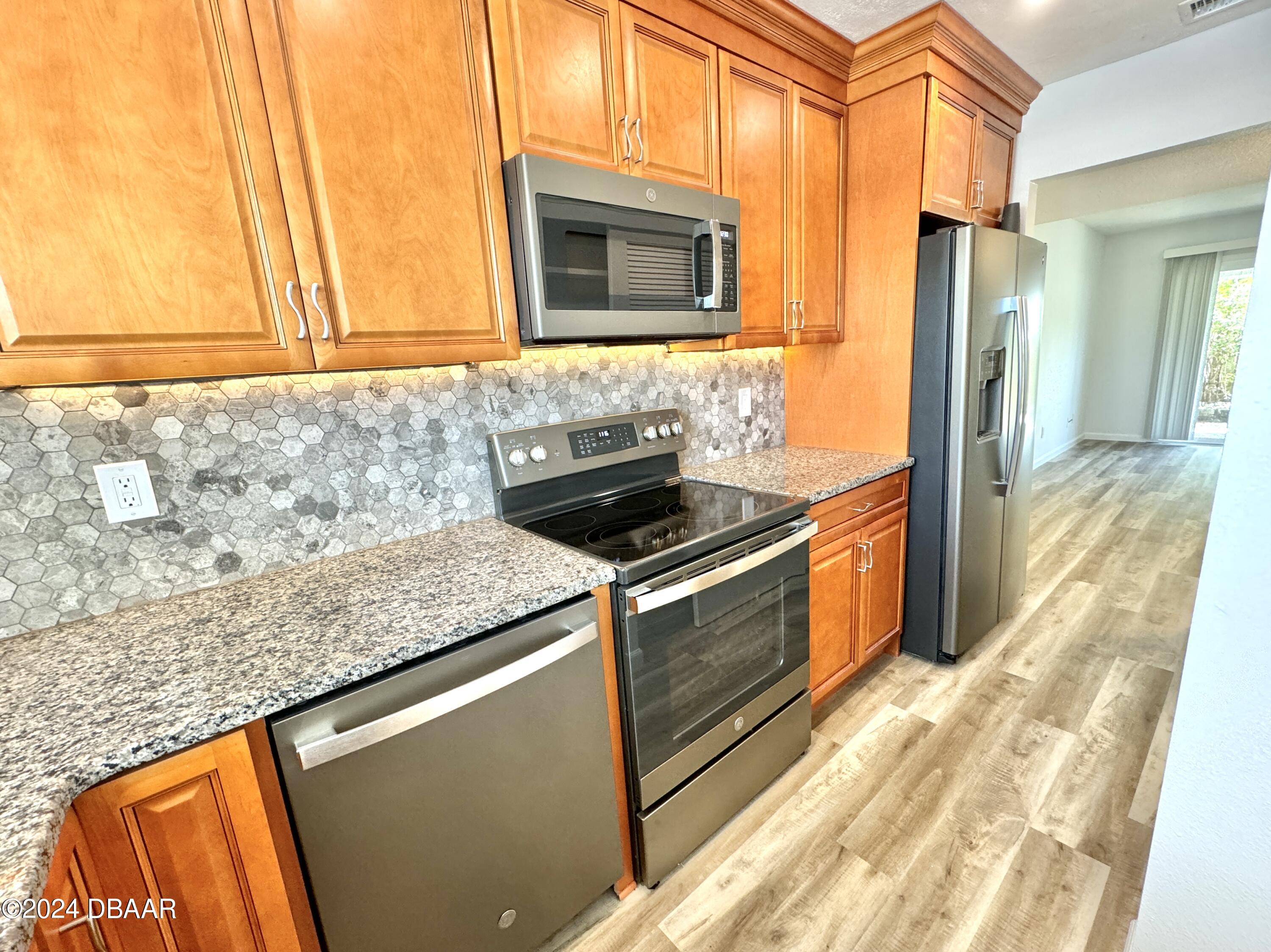 a kitchen with granite countertop cabinets stainless steel appliances and a counter space