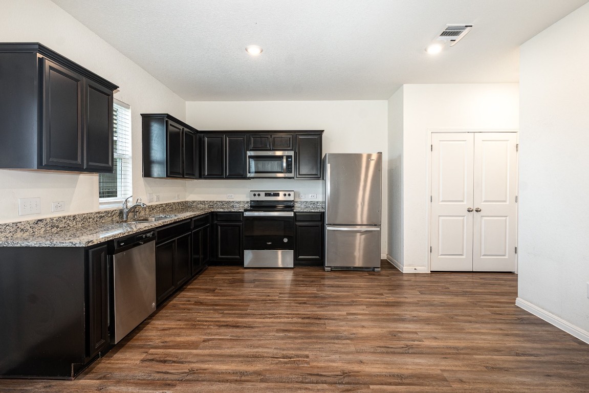 a kitchen with stainless steel appliances granite countertop a refrigerator and a stove top oven