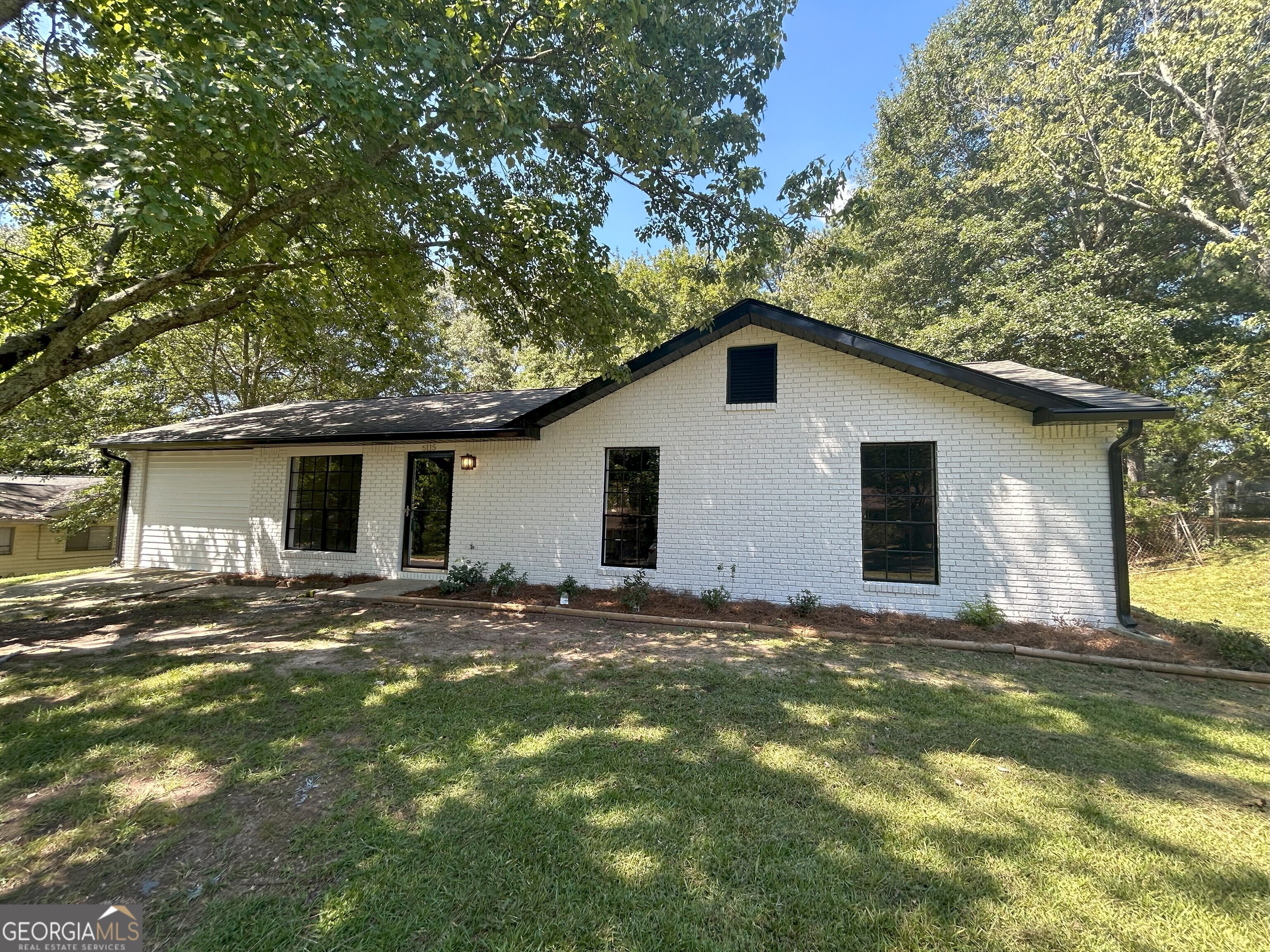 a view of a yard in front of a house with large tree