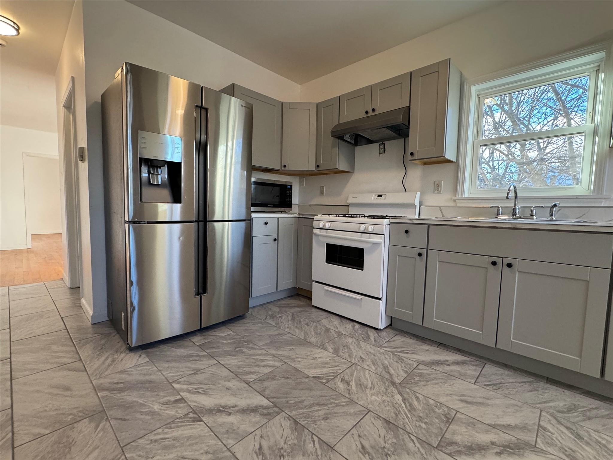 Kitchen with gray cabinets, sink, and appliances with stainless steel finishes