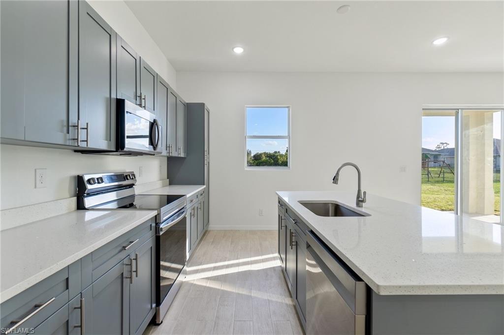 a kitchen with stainless steel appliances granite countertop a sink a stove and a wooden cabinets